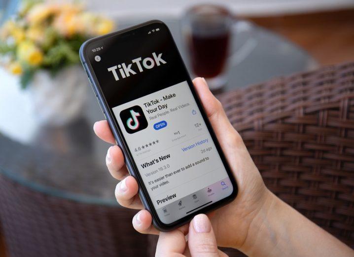 A person is holding a phone with the TikTok app open.