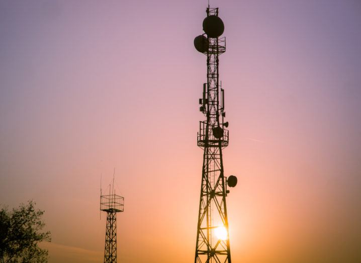 A 5G radio tower against a clear, purple and orange sky at sunset.