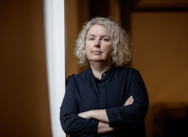 Prof Linda Doyle, the new provost of Trinity College Dublin, is standing with her arms folded while looking into the camera.