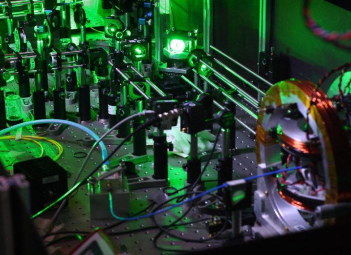 Laboratory equipment is set up under green lighting for quantum physics experiments.