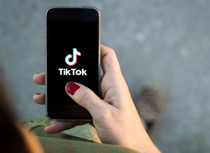 A person’s hand holding a black smartphone with the TikTok logo on the screen.