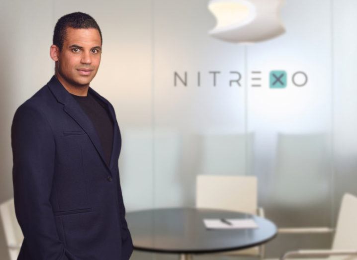 A man stands in an office in front of a sign that says Nitrexo.