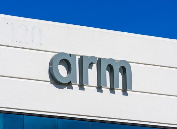 The Arm logo on the side of a building underneath a blue sky.