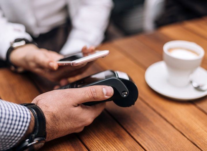 Woman paying for coffee by mobile phone in a restaurant.