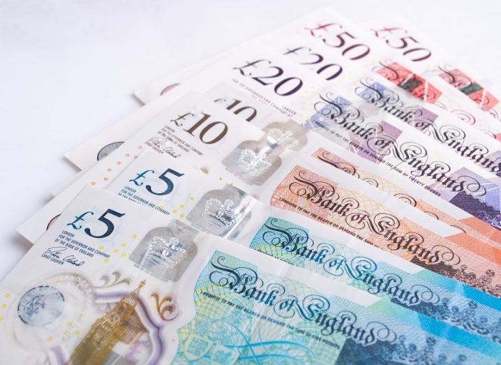 UK pound notes are spread against a white surface.