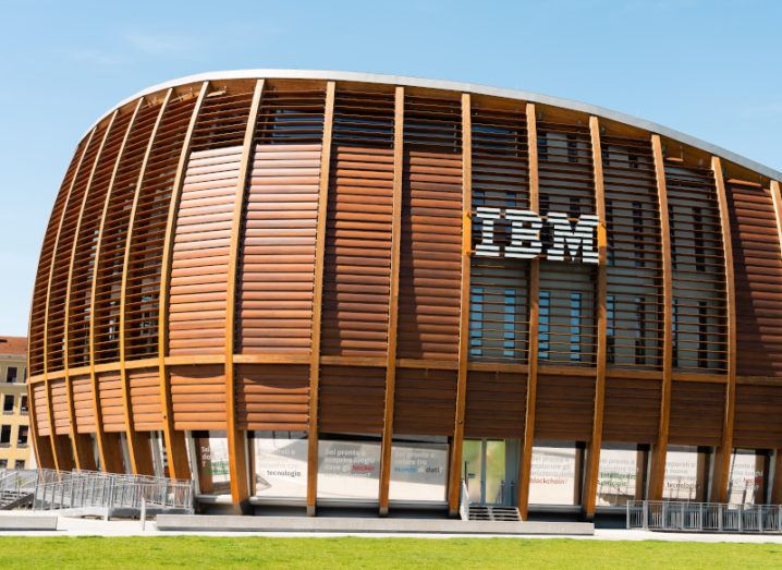 A large wooden building with the IBM logo on the side is shown under a bright blue sky.