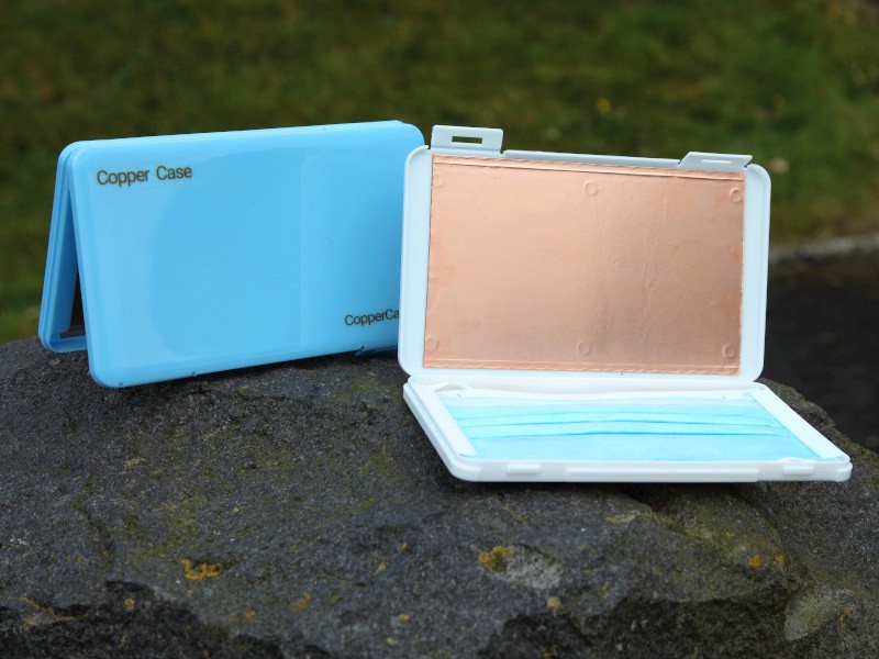 A blue case is open, showing a sheet of copper on one side and a face mask on the other.