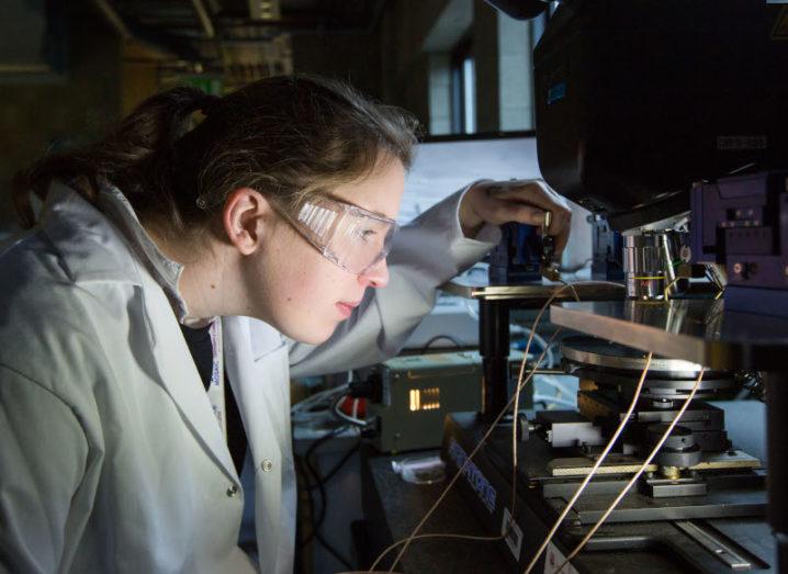 Dr Sarah Geurin is wearing a lab coat and goggles, using a scientific instrument in a lab setting.