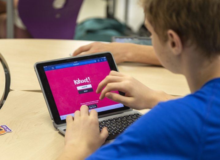Child in school using a tablet that says 'Kahoot' on the screen.