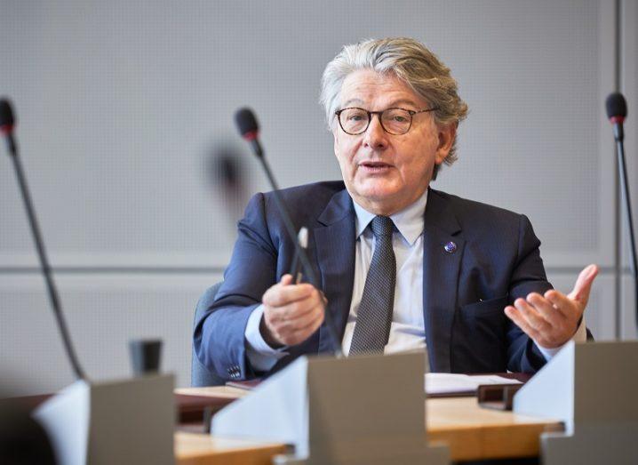 Thierry Breton is sitting at a conference table in front of a microphone.