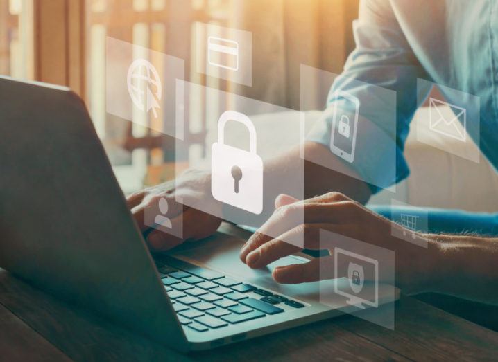 A man's hands are working at a laptop, while images of padlocks and other security features float above the keyboard.