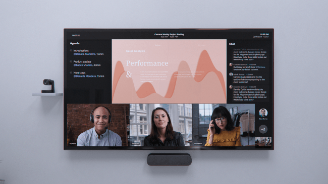 A large screen showing Microsoft Teams with its new front row feature with three remote employee screens along the bottom.