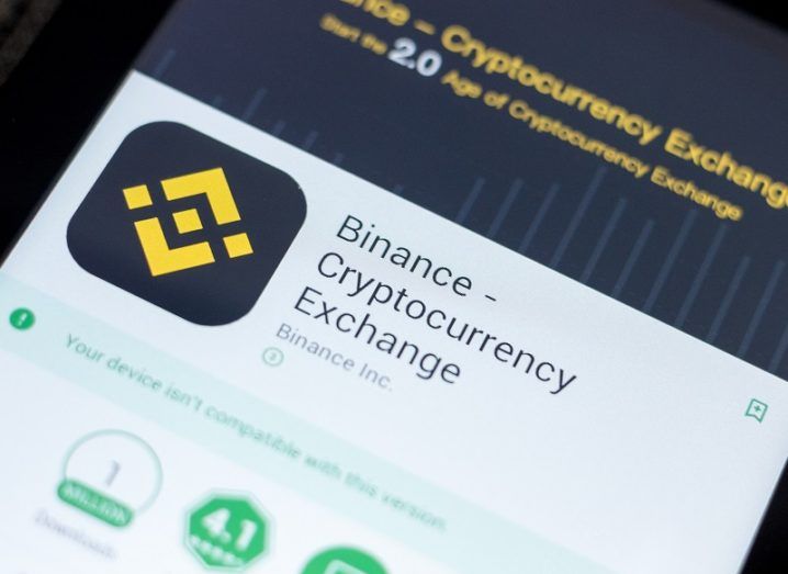 A phone screen is showing an app store with the details of the Binance app.
