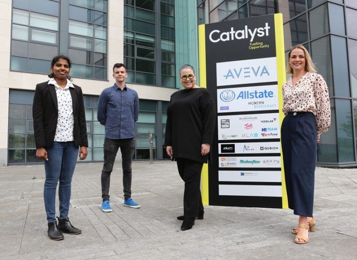 Four people stand outside beside a sign for the Catalyst hub.