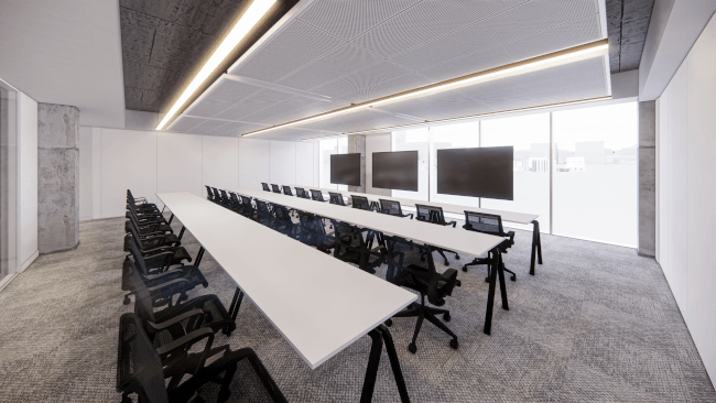 A training room with three long tables with many seats in front of three large screens.