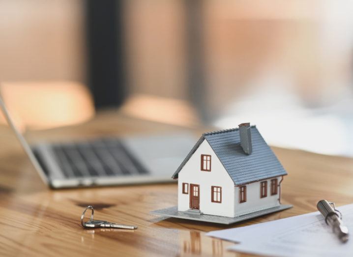 A stock image of a model house beside a key, a laptop, and several documents.