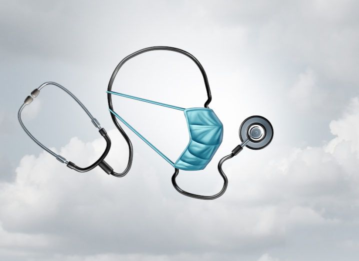 Stethoscope suspended in mid-air made to look like a head wearing a medical mask. Sky background.