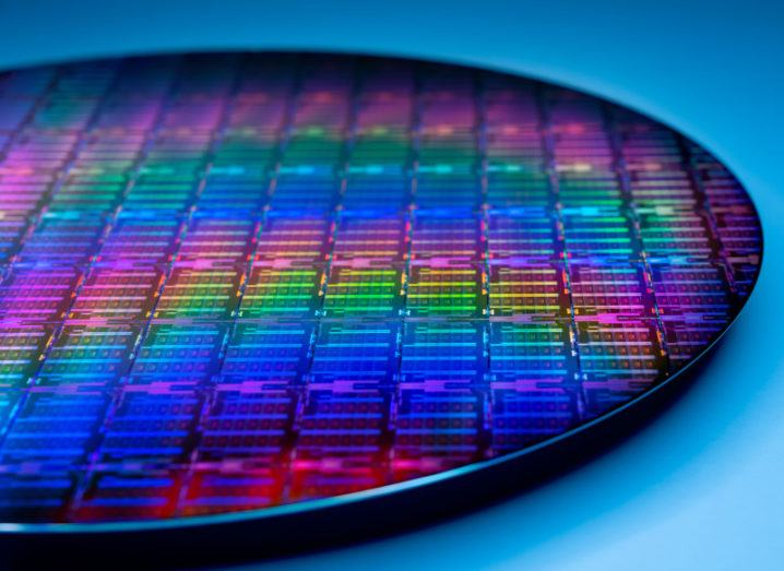 A thin disc of silicon wafer reflecting a full spectrum of colour on its surface.