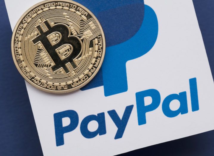 A Bitcoin coin sitting on top of the PayPal logo.