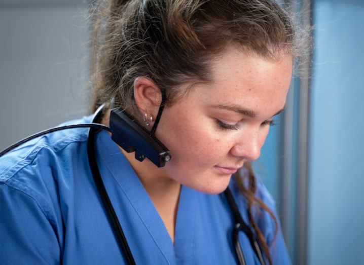 A medical professional wearing the BlueEye Handsfree device around her ear..