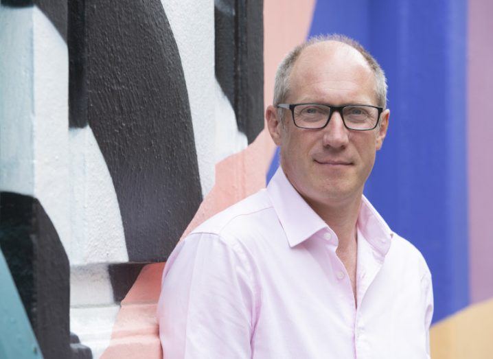 Spark Crowdfunding CEO Mark Burge is standing in front of a colourful wall.