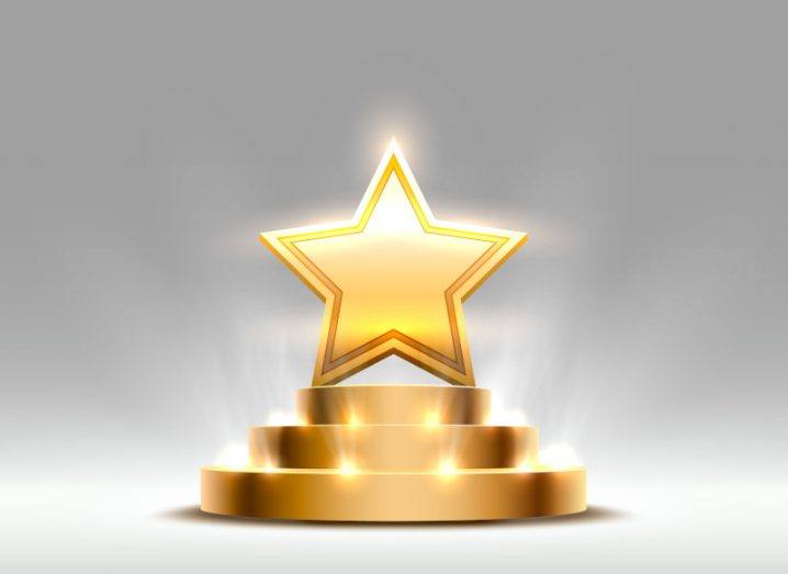 An artist’s digital depiction of a golden star award is shown. The star is on a podium and is lit up by yellow lights, indicating the winners of the Breakthrough Prizes.