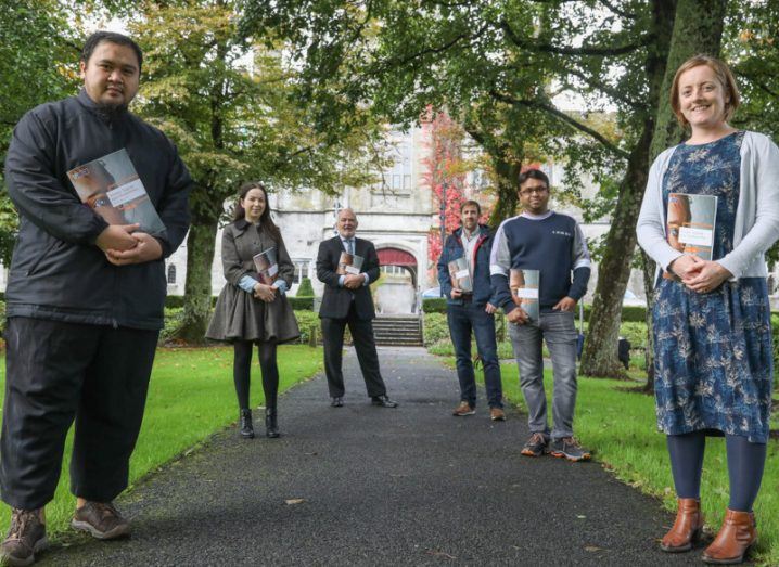 Six people who are members of NUI Galway research community standing outside on the campus surrounded by trees.