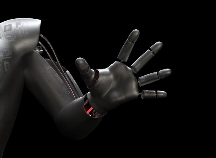 Robotics hand reaching out with open palm against a dark background.