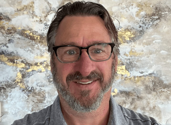 A headshot of Frank Poore against a colourful background.