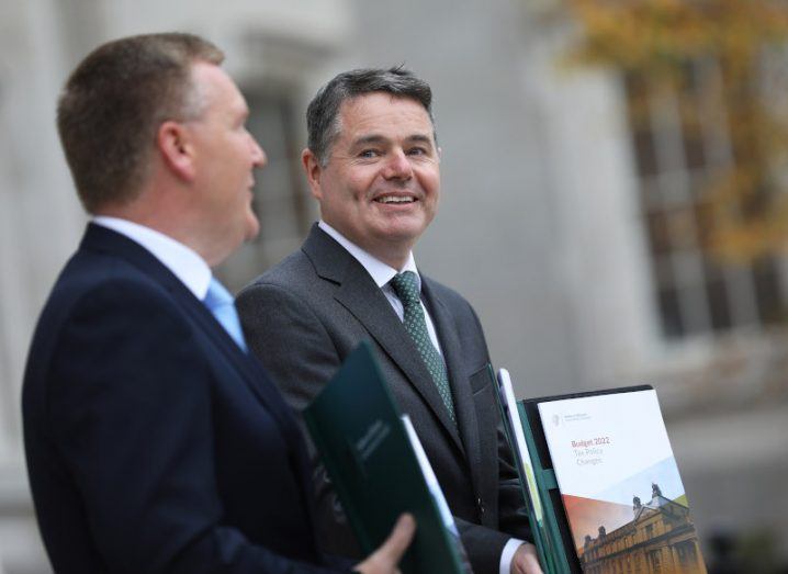 Two men stand outside holding copies of the Budget.