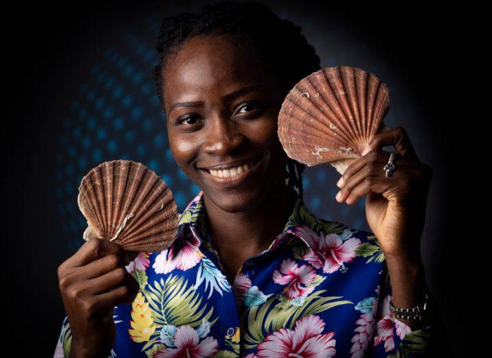 Postgraduate researcher Brakemi Egbedi holds shells up to her face and smiles. Her project focuses on the possible pharmaceutical uses for shell waste.