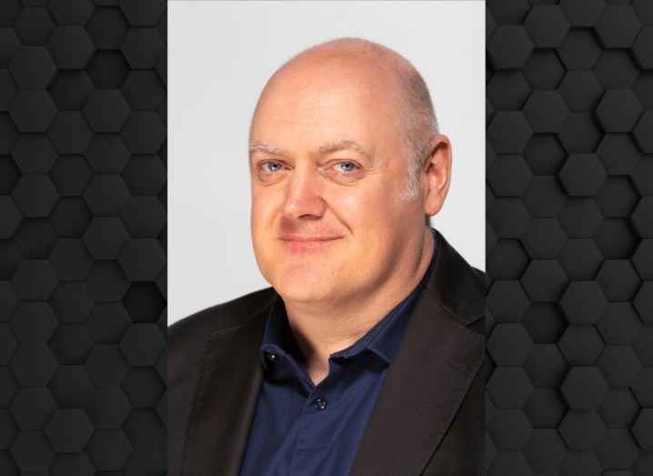 Headshot of Dara O Briain wearing a suit, against a dark background.