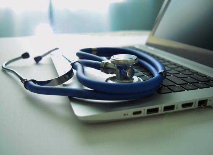 A blue stethoscope rests on a laptop keyboard.