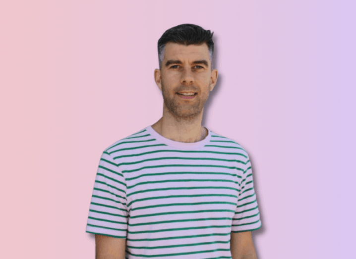 Publift founder Colm Dolan in a blue and white striped shirt against a soft pink background.