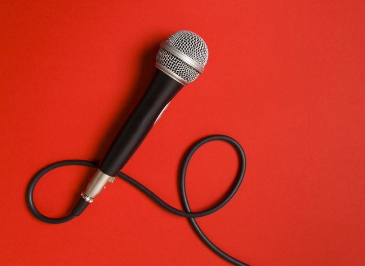 Microphone connected to a lead left lying against a vivid red background.