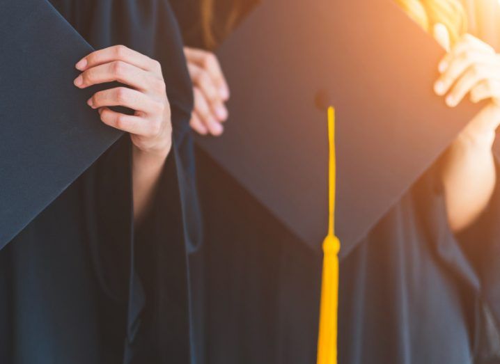 A close-up image of hands clutching a graduation cap.
