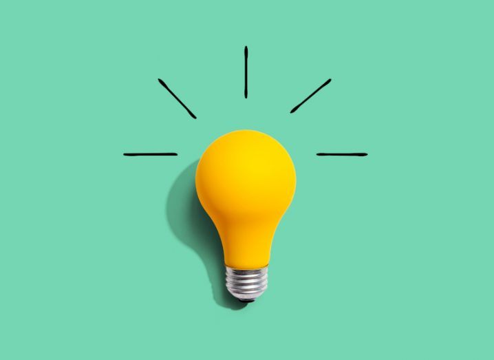 A bright yellow lightbulb against a pale green background.