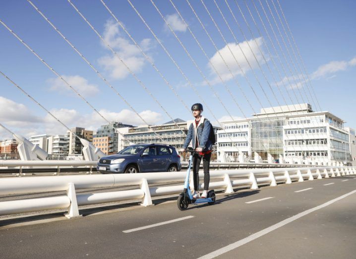 A person riding a Dott e-scooter over a bridge in Dublin city.