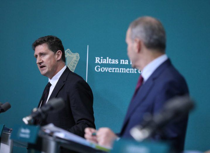 Photo of Minister Eamon Ryan in focus with Taoiseach Micheál Martin looking towards him in the foreground. The two are speaking at the launch of the Climate Action Plan.