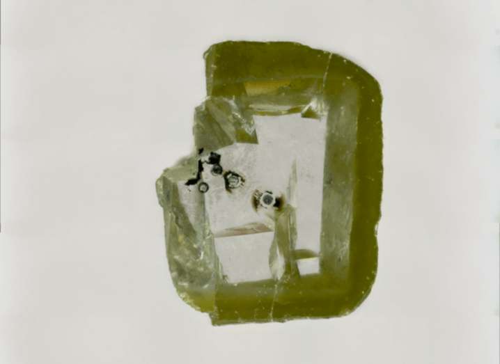 Black spots of davemaoite enclosed in a greenish, unpolished diamond.