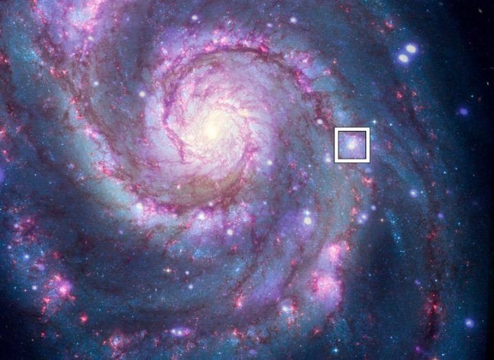 A white square surrounds the location of a possible planet researchers have found in the middle of a galaxy bathed in purplish light.