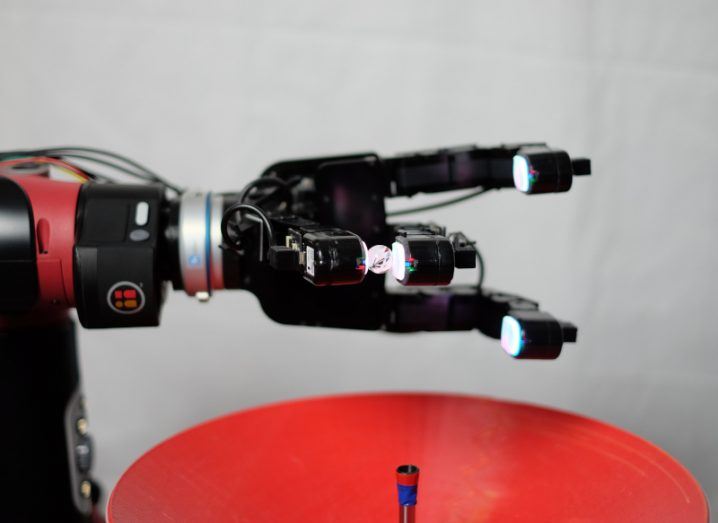 Black robotic hand holding a glass marble.