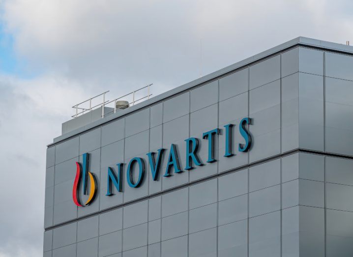 Novartis logo on its building in Stein, Switzerland. A cloudy sky is above it.