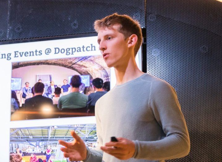 Tom McCarthy, founder of Patch, talking at an event with a screen behind that partially reads "Events at Dogpatch". He is a young man wearing a grey sweater.