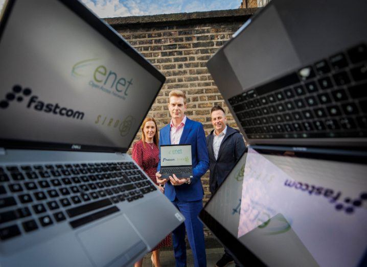 Lorraine Gibbons, Cormac Ryan and Ronan Whelan, with laptops to the side. Cormac is holding a laptop and there is a wall behind them.