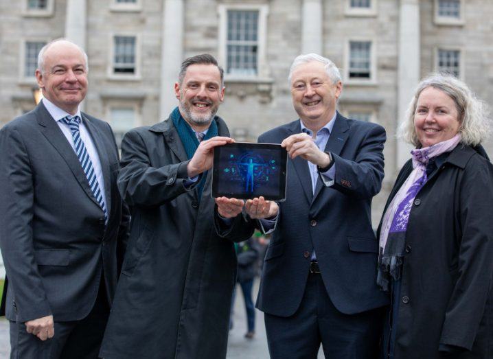 Three men and one woman smiling standing outside TCD celebrating the Adapt Centre's partnership with the HSE.