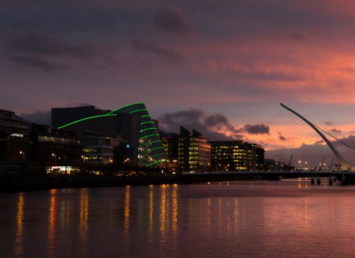 Dublin city with a sunrise in the background. The Convention Centre Dublin has green lights.