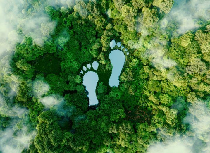 Aerial photo of a green forest with a lake in the shape of two footprints.