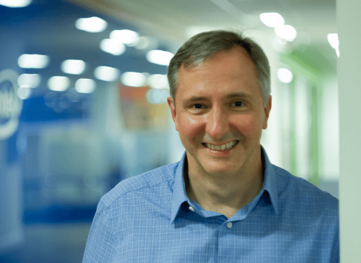 A man in a blue shirt stands in a factory setting.