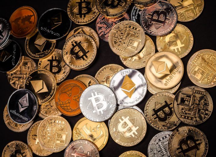 Golden and silver coins with the logos of various cryptocurrencies on them, including Bitcoin and Ethereum.